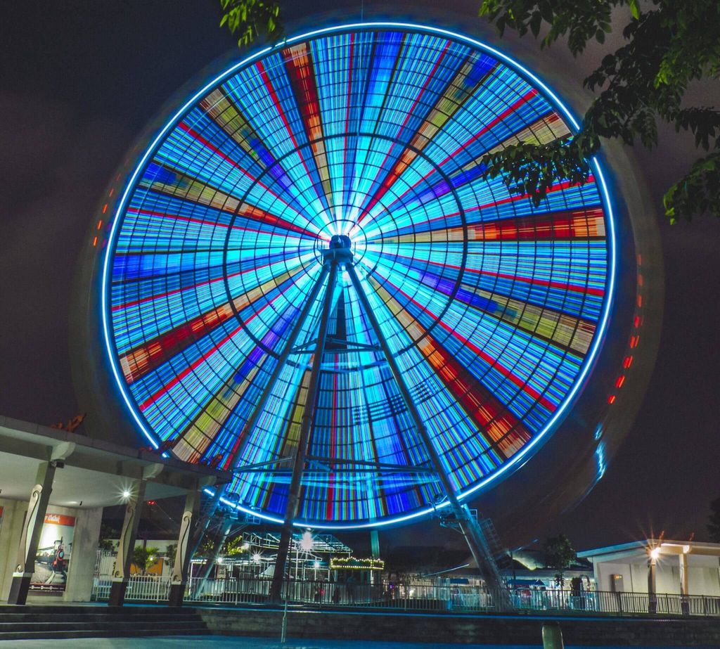 Ferris wheel illuminated with vibrant colors at night.