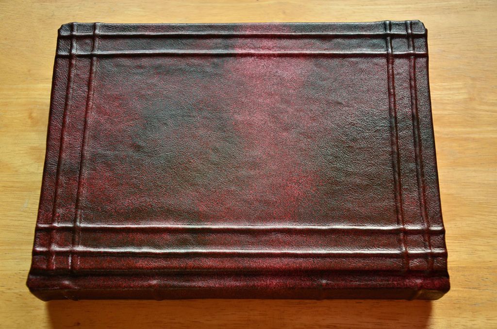 Buku kulit merah dengan bordir vertikal di sisi kanan.