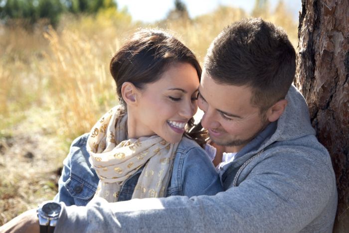 Pasangan romantis berpelukan di dekat pohon di taman musim gugur.