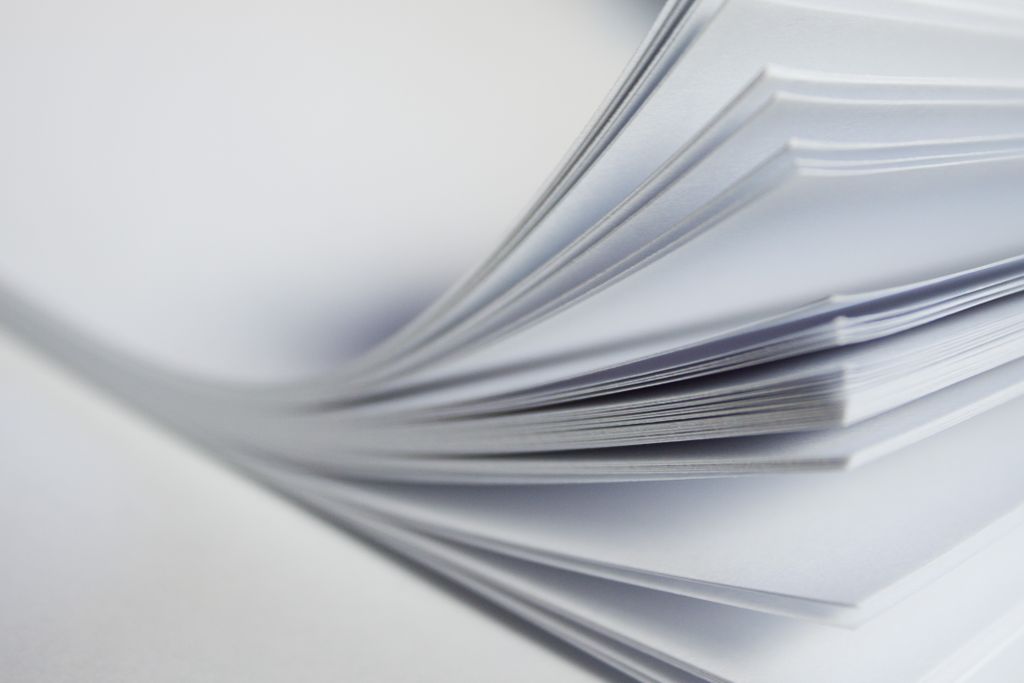 Close-up view of a stack of white papers on a light background.