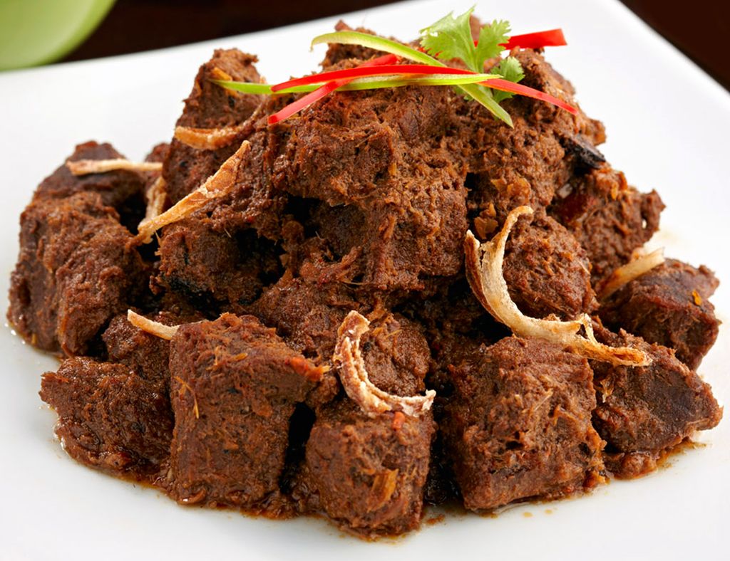 Porsi makanan daging masak dengan saus hitam dan irisan bawang.