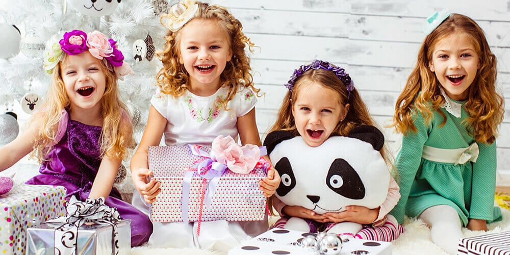 Empat anak kecil senang berpose dengan hadiah berbentuk panda dan kado-kado lainnya.
