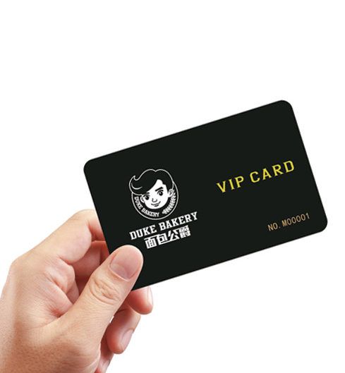 Tangan memegang kartu VIP Duke Bakery dengan desain unik sebagai contoh media cetak yang dapat diarahkan ke program loyalitas digital.