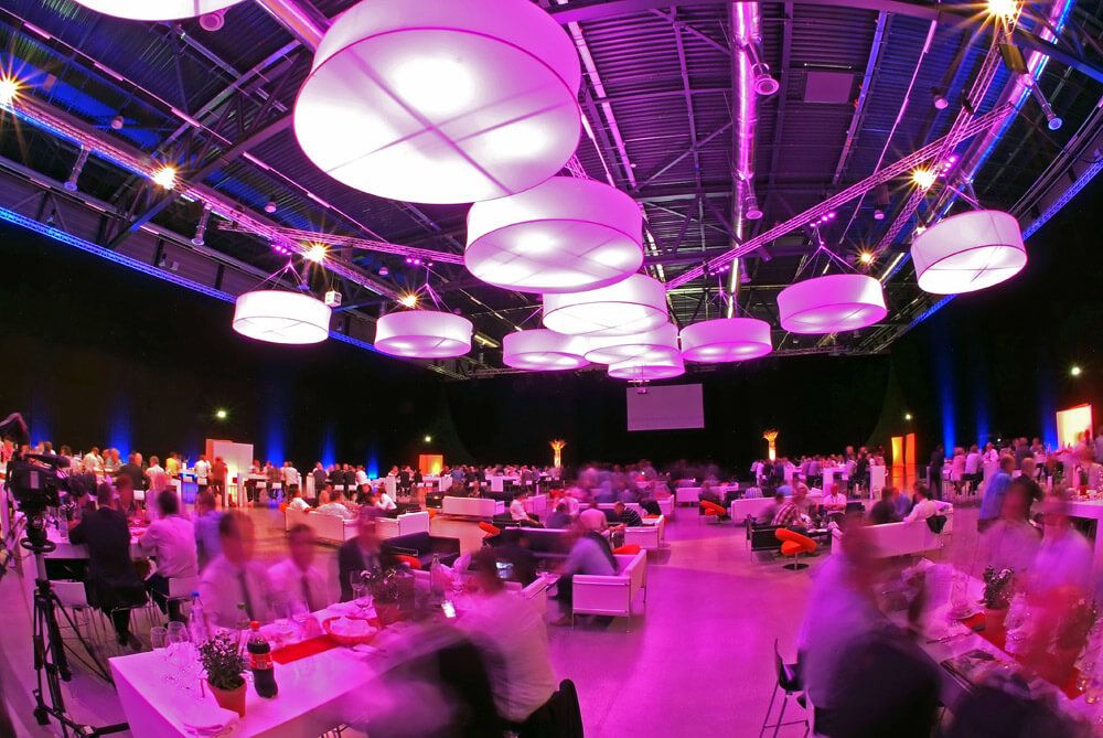 Gala dinner di ruangan luas dengan lampu modern dan tamu yang berbincang-bincang