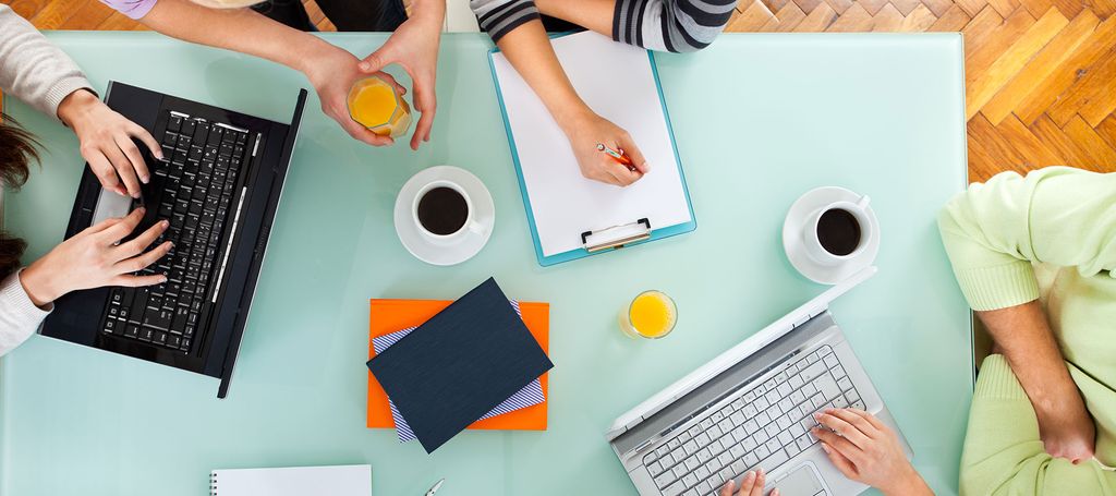 Orang-orang bekerja di meja kerja dengan laptop dan kopi
