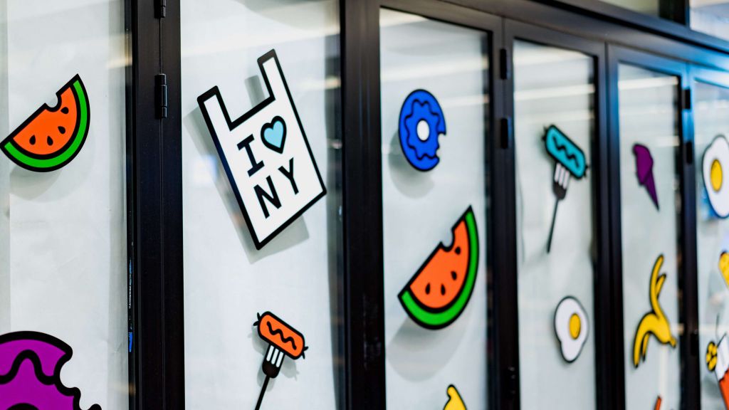 Stiker berbagai makanan dan ikon di pintu kaca, menunjukkan desain grafis untuk percetakan online.