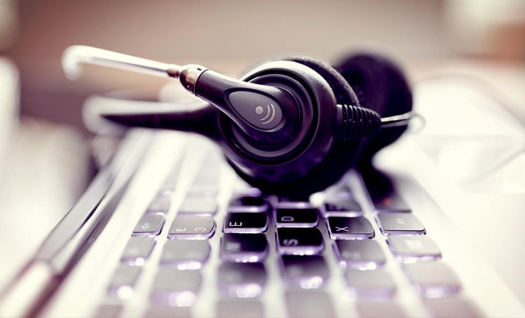 Headset dengan microphone terletak di atas keyboard laptop, siap digunakan untuk komunikasi suara.