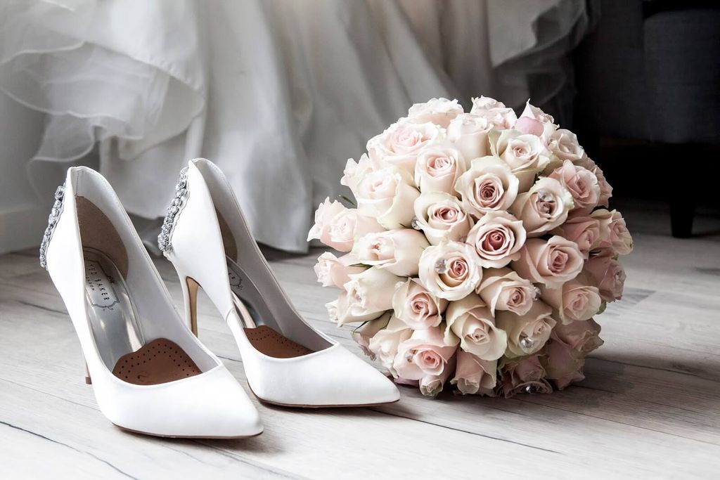 Sepatu pengantin putih elegan dengan buket mawar pink dan putih