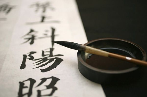Alat tulis tradisional berisi tinta dengan kertas tulisan berwarna putih dan tulisan karakter Cina.