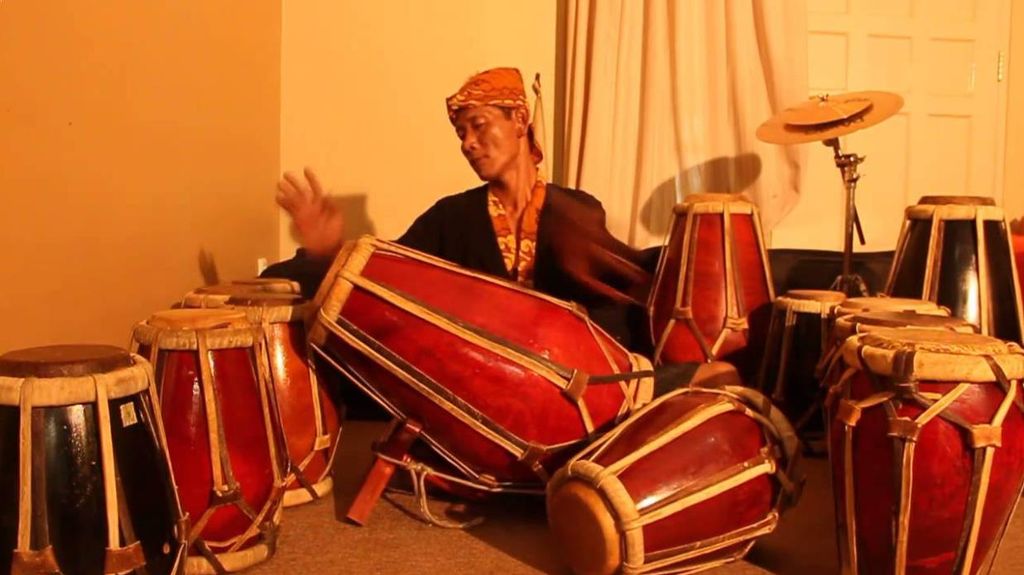 Orang memainkan alat musik tradisional di ruangan.