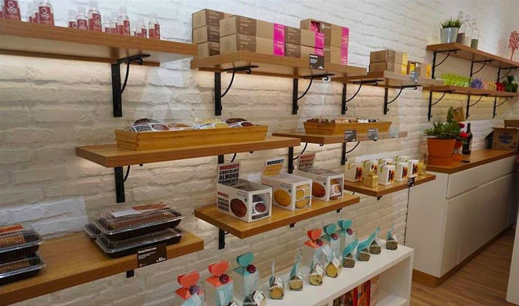 Rak rak produk di toko percetakan Uprint.id dengan berbagai jenis kue dan makanan.