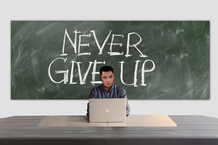 Orang muda belajar di depan papan tulis 'NEVER GIVE UP'.