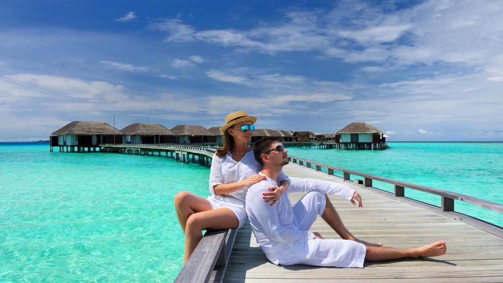 Pasangan menikmati pemandangan pantai tropis dari dock.