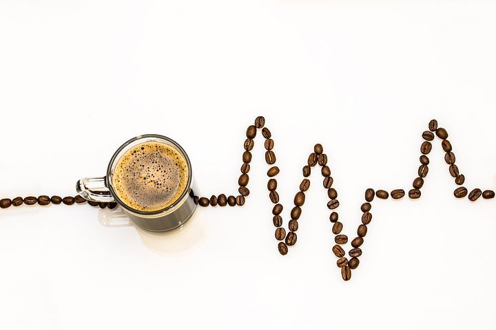 Cangkir kopi dengan kardiofogram di sekelilingnya dibuat dari biji kopi.