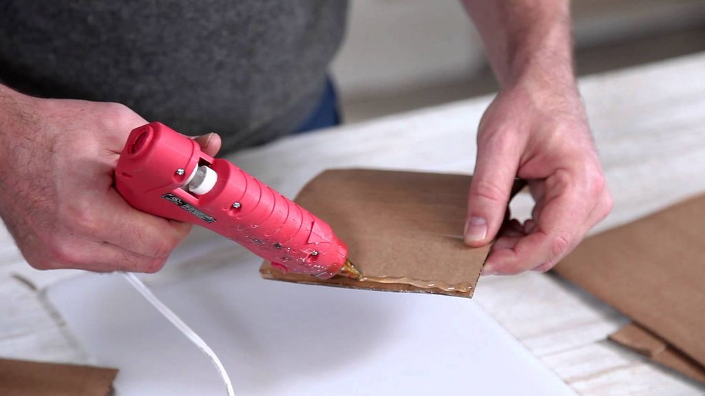 Tangan menggunakan glue gun untuk menempelkan lembaran karton