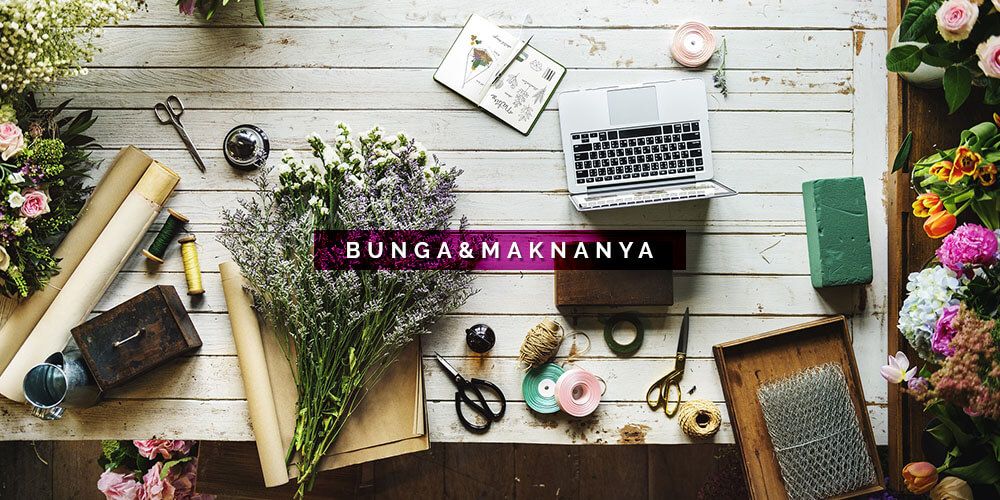 Meja kerja dengan laptop, alat bunga, dan bunga segar.