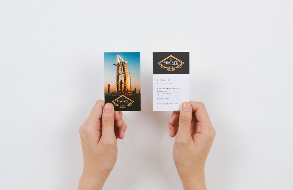 Tangan memegang kartu nama Vingate Hotel & Resort dengan latar Burj Al Arab di depannya.
