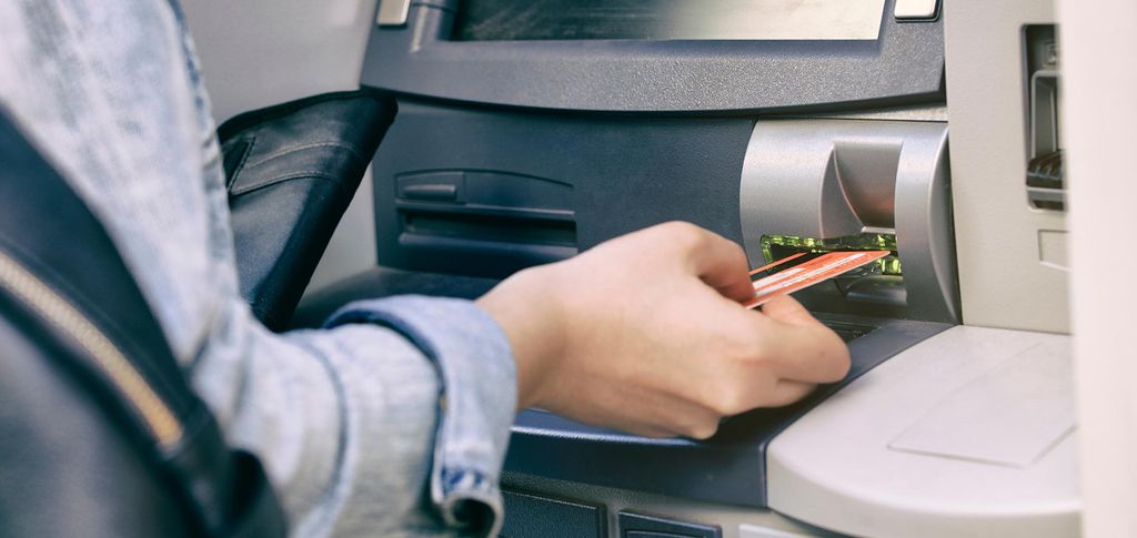 Tangan memasukkan kartu ATM ke mesin ATM