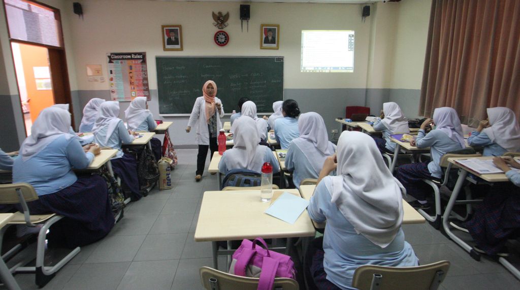 Guru dan siswa dalam kelas online dengan peralatan modern.