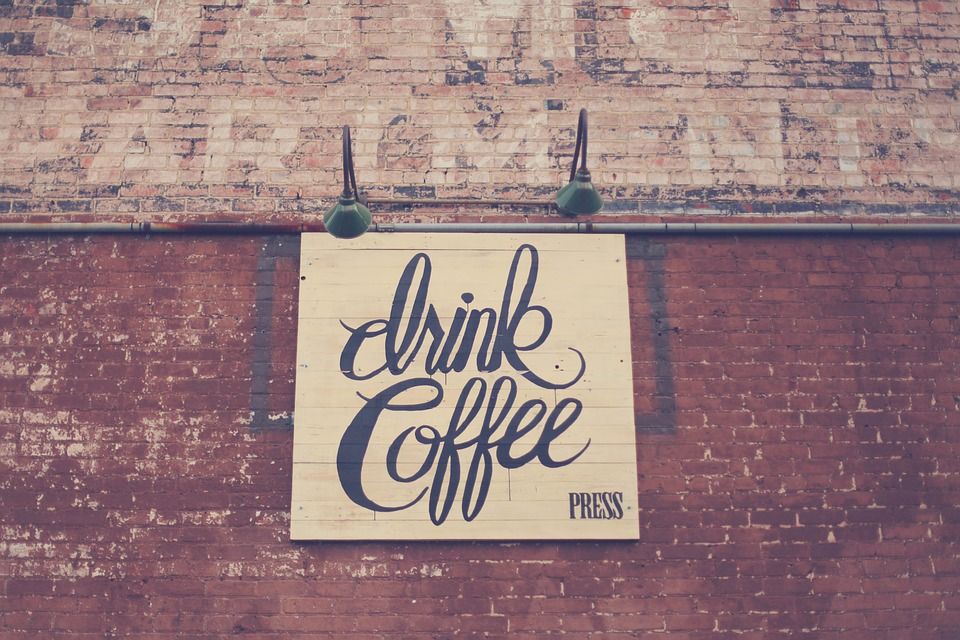 Tanda Drink Coffee Press di dinding batu desain modern sebagai ilustrasi distribusi flyer coffee shop baru