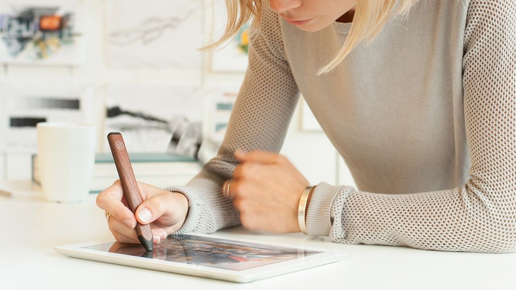 Perempuan menggunakan stylus untuk menggambar di tablet.
