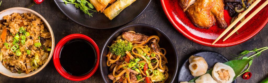 Pilihan makanan Asia dengan nasi goreng, mie goreng, ayam bakar, dan saus.