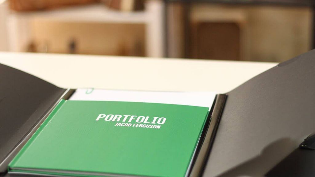 Tas portofolio hijau dengan tulisan 'PORTFOLIO JACOB FERGUSON' di depannya.
