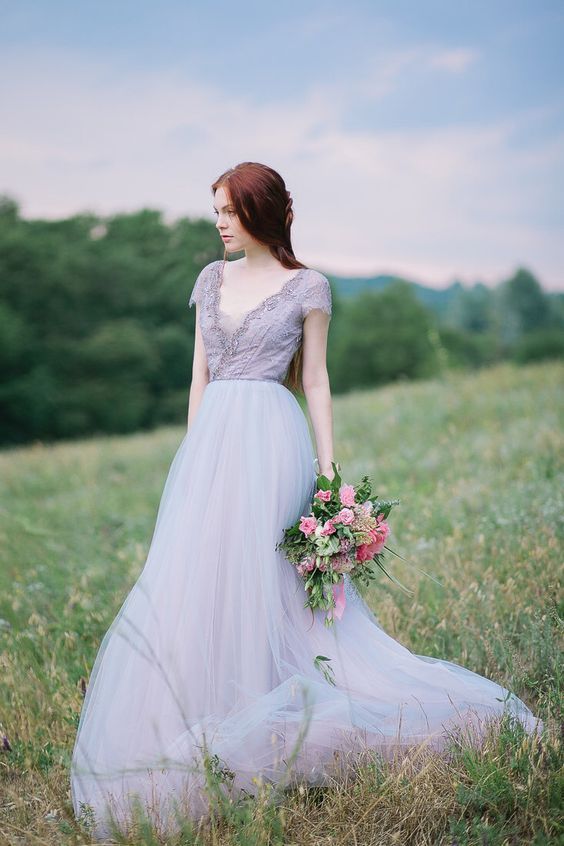 Perempuan memegang buket bunga di lapangan hijau dengan gaun elegan.