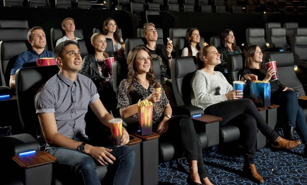 Grafik menunjukkan orang-orang menikmati makanan dan minuman di bioskop.