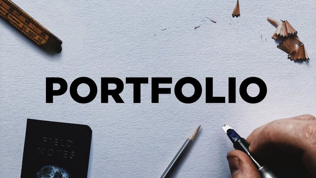 Tulisan 'PORTFOLIO' di atas meja dengan alat tulis dan buku catatan