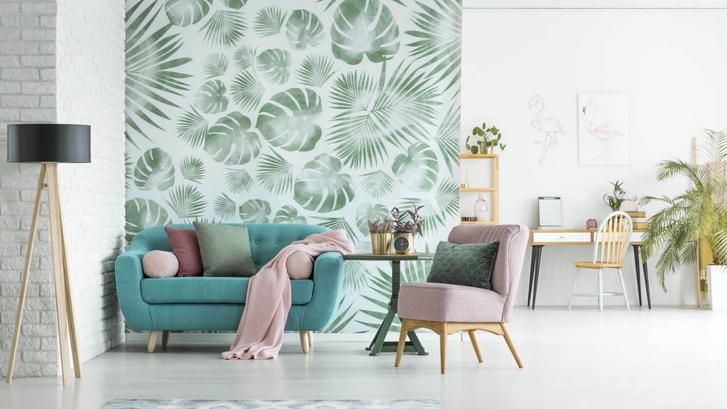 Dinding wallpaper tropis hijau dan putih di ruang tamu minimalis modern dengan sofa biru dan meja kayu.