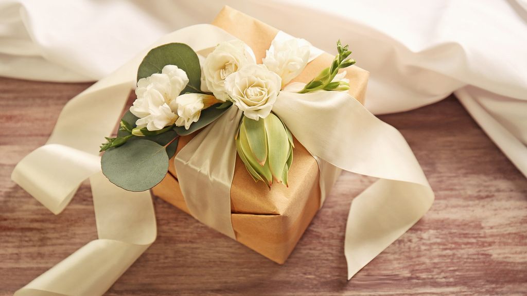 Paket hadiah elegan dengan kertas kraft dan bunga putih, cocok untuk acara formal.