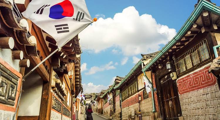 Pemandangan jalan khas Korea dengan bangunan tradisional dan bendera Korea di sisi kiri.