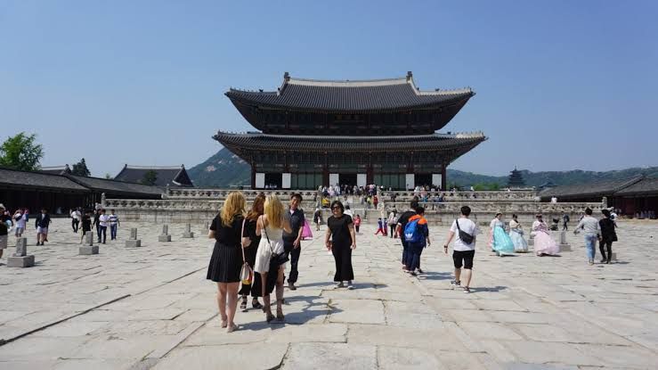 Istana Gyeongbokgung di Seoul, Korea Selatan dengan pengunjung berjalan di depannya.
