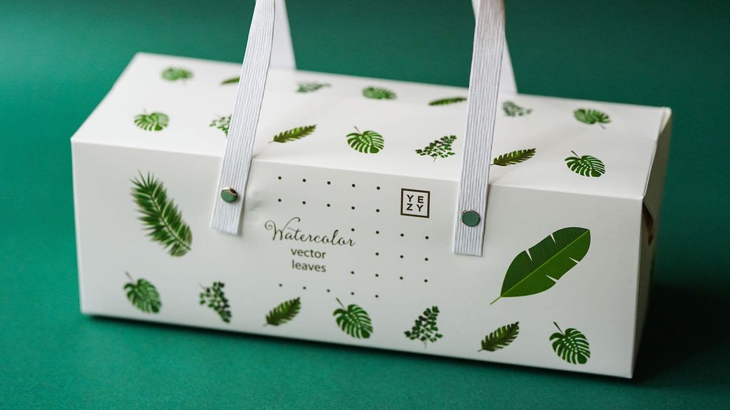 Kotak hadiah putih dengan motif daun air dan logo 'YEZY' di bagian tengah.