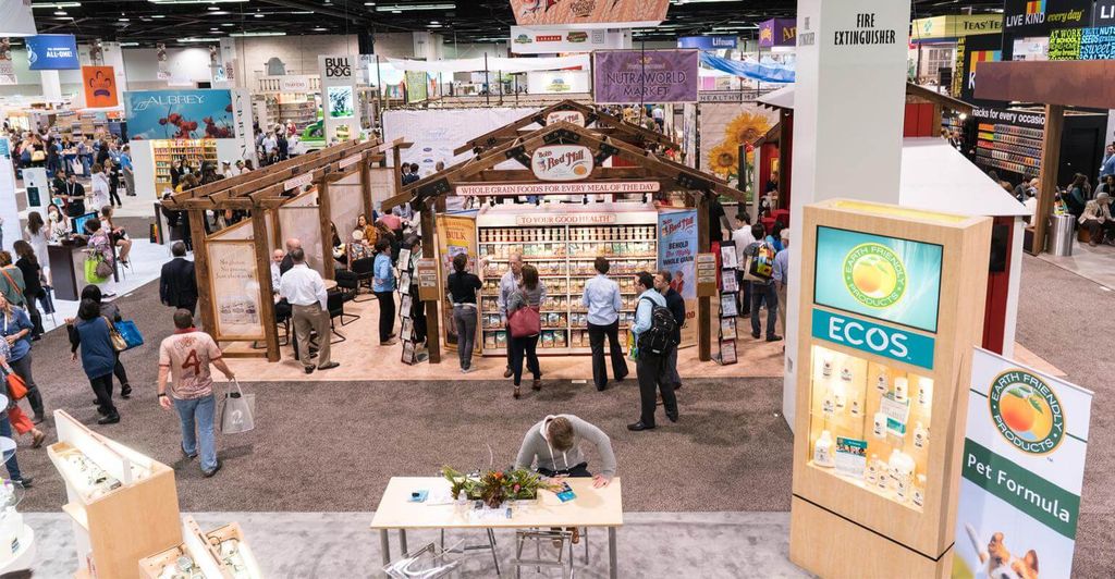 Pemandangan pameran produk makanan dan perawatan alami dengan pengunjung sibuk.