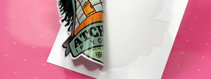 Stiker dengan desain unik dan tulisan 'ATCH YOURSELF' di atas latar biru dan oranye.