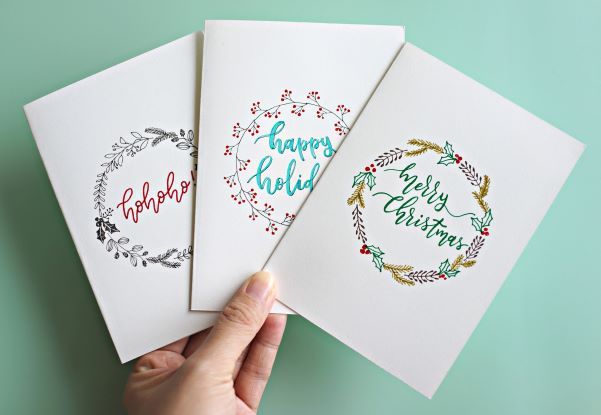 Tiga kartu Natal putih dengan desain unik dan tulisan bahasa Inggris.