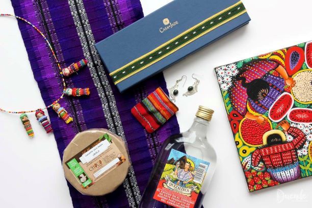 Paket hadiah eksotis dengan serbaneka budaya Meksiko, termasuk kain tradisional, cokelat, dan minuman alkohol.