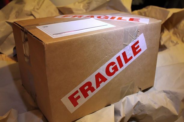 Karton kecil bertuliskan 'FRAGILE' dengan label pengiriman.