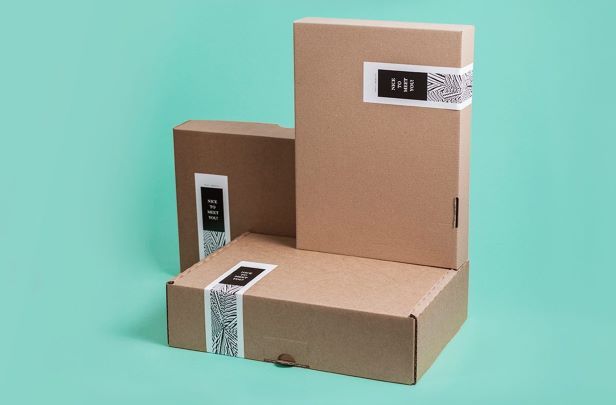 Tiga kotak karton berukuran berbeda dengan label minimalis di depan latar biru.