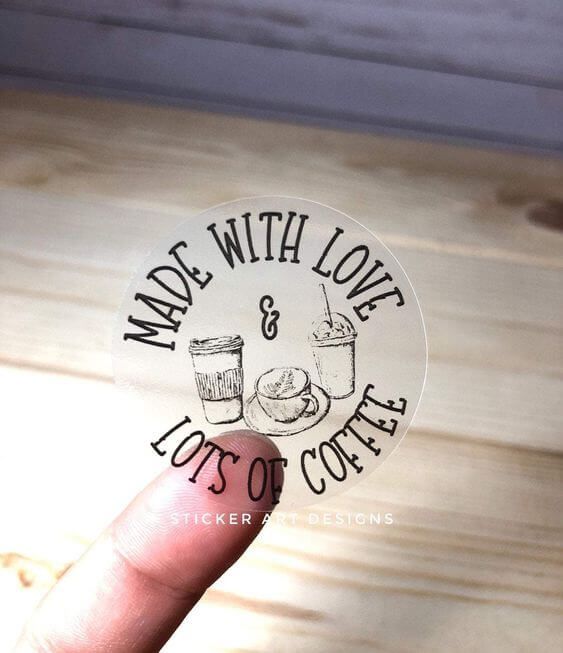 Stiker transparan berbentuk bulat dengan tulisan 'Made with Love & Lots of Coffee' dan gambar cangkir kopi, cocok untuk dekorasi atau label.