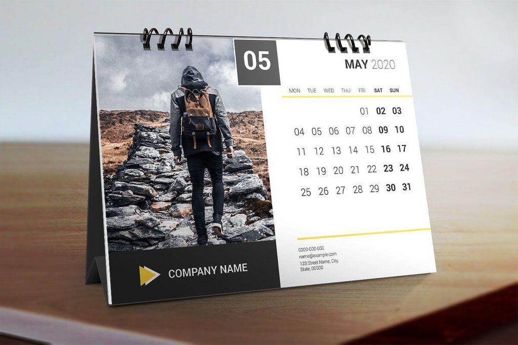 Kalender meja bulan Mei 2020 dengan foto pendaki gunung di depannya.
