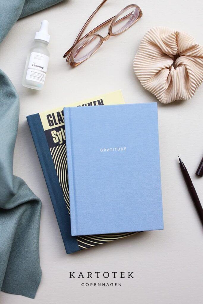Buku agenda besar dengan jilid hardcover diletakkan di atas meja kerja kayu minimalis