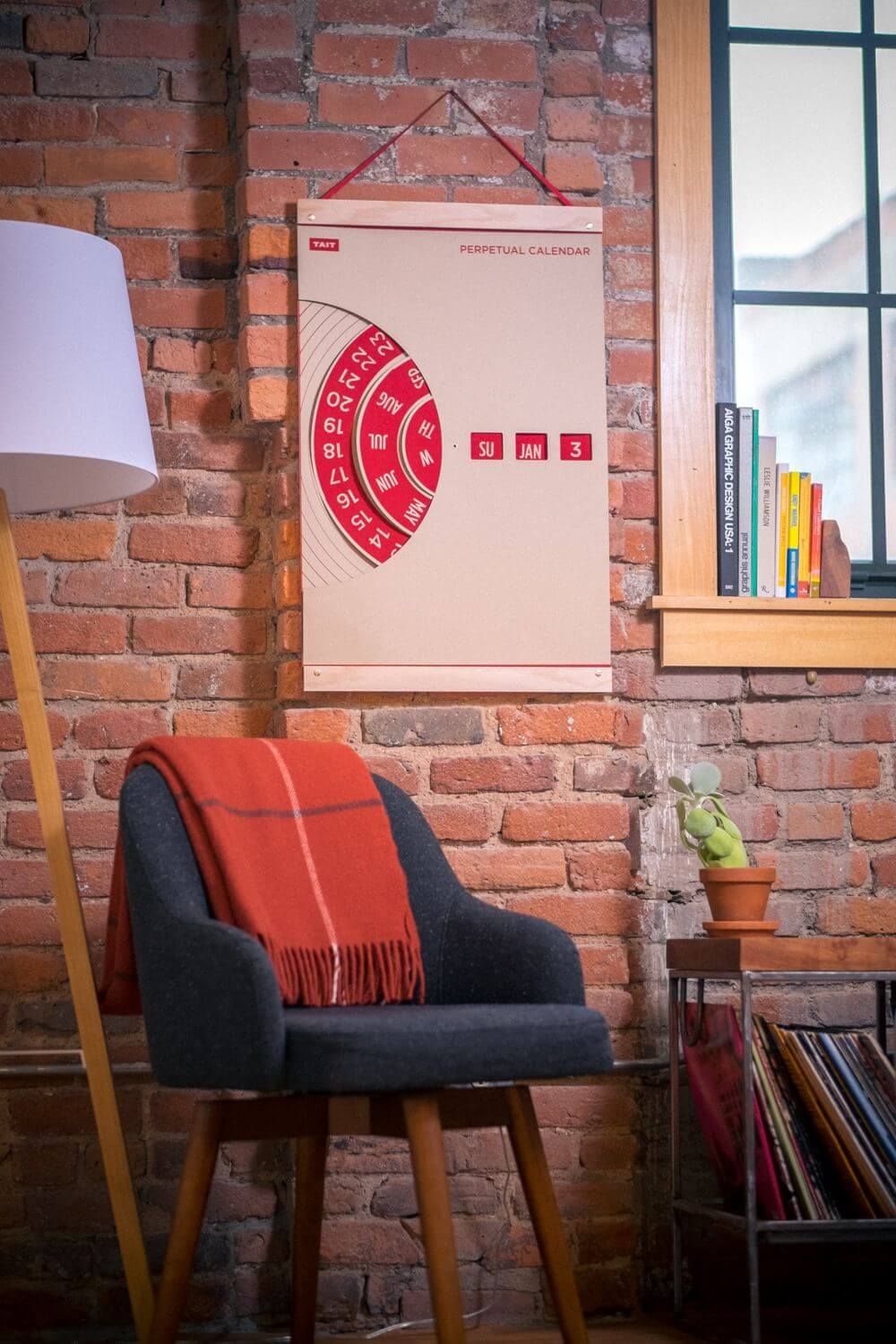 Perpetual calendar mounted on a brick wall in a cozy room setting.