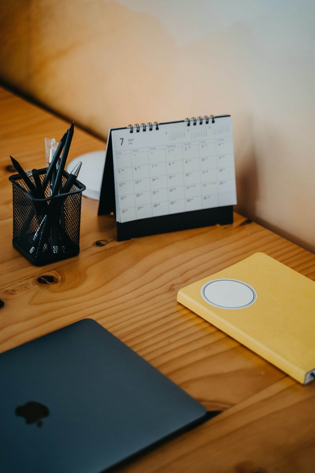 Meja kerja minimalis dengan laptop, kalender, dan catatan