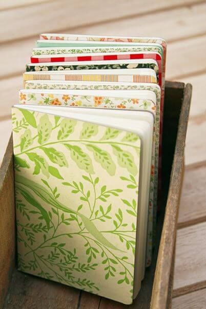 Serangkaian buku bermotif dalam kotak kayu sebagai ilustrasi pilihan finishing dan tampilan dokumen cetak yang lebih premium.