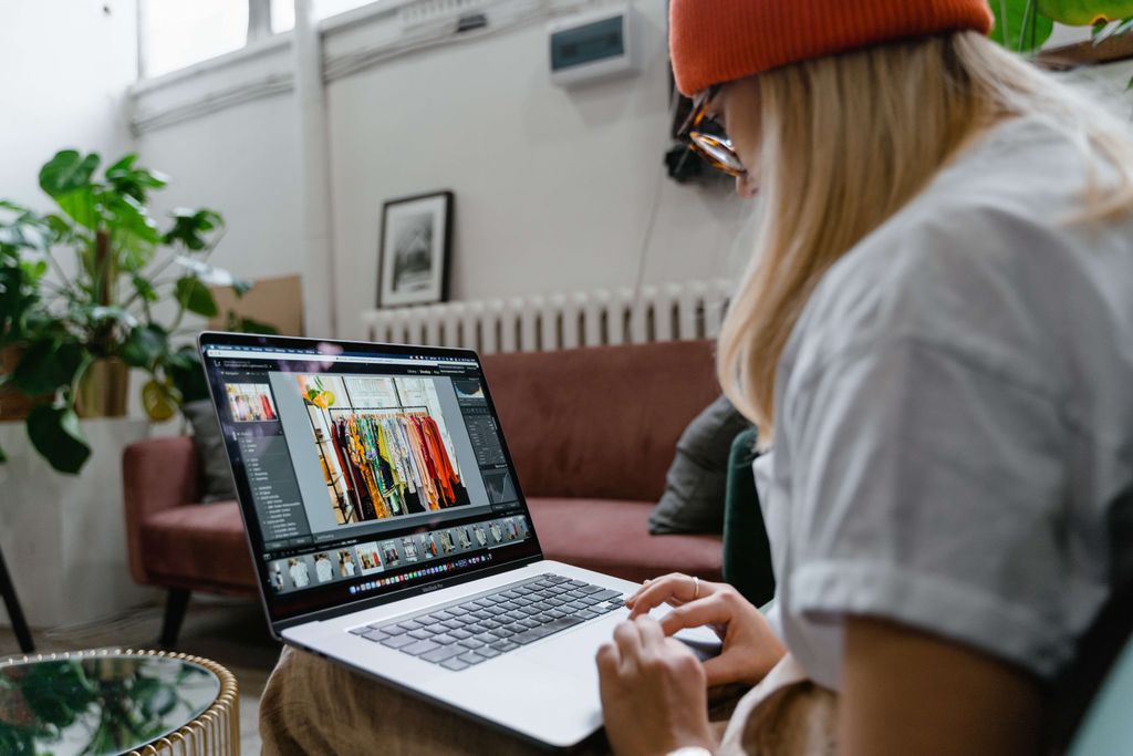 Desainer grafis sedang bekerja di laptop dengan software desain grafis terbuka.