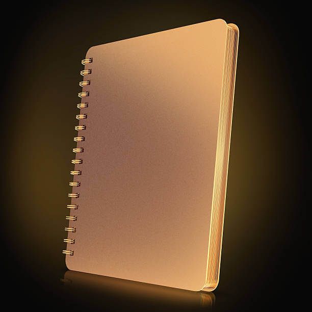 Notebook spiral dengan cover emas dan halaman putih.