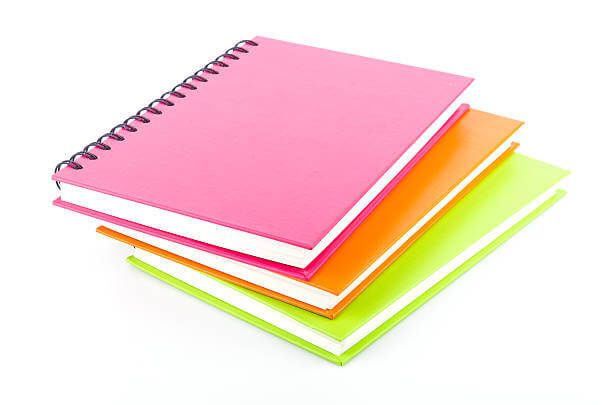 Tiga buku spiral berwarna cerah berbaring bersama.
